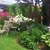 Grüner Garten mit blühenden Beeten, Gartenstuhl aus Holz