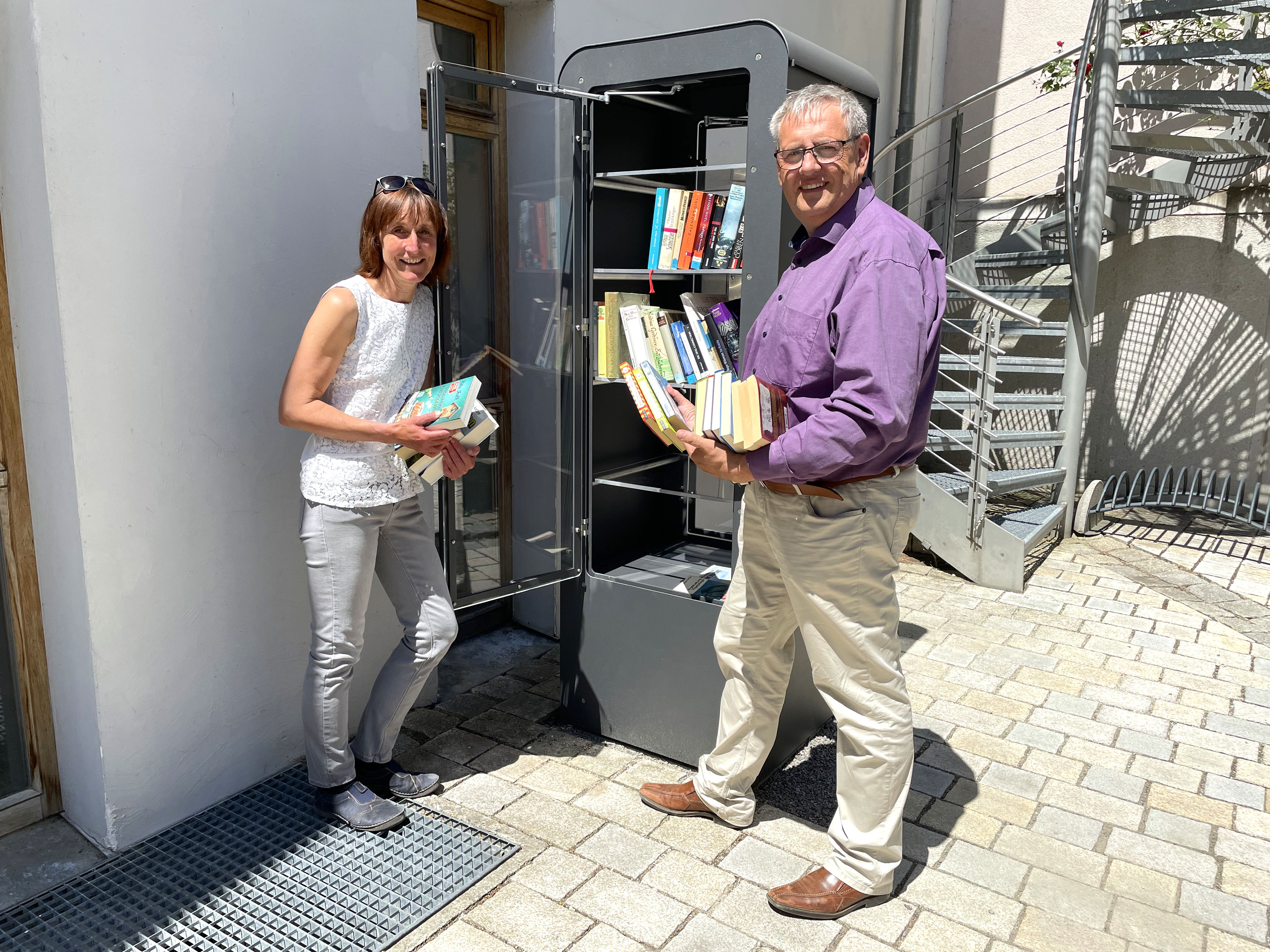 Bürgermeister Herbert Tischhöfer und Bibliotheksleiterin Karola Künzl befüllen den Bücherschrank vor dem Hemauer Zehentstadel.