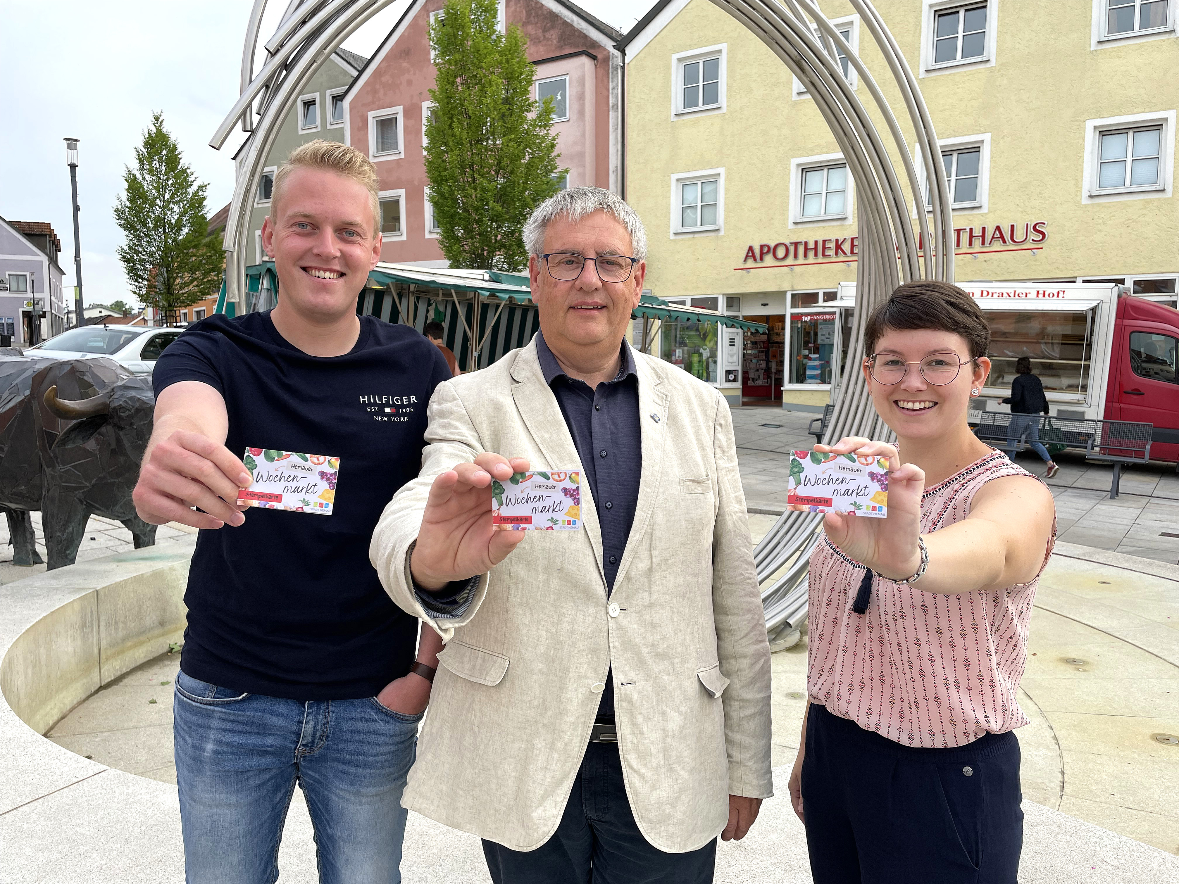 Bürgermeister Herbert Tischhöfer (Mitte) und die beiden Marktmeister Lena Scheuerer (rechts) und Andreas Ehrl (links) präsentieren die neue Wochenmarkt-Stempelkarte.